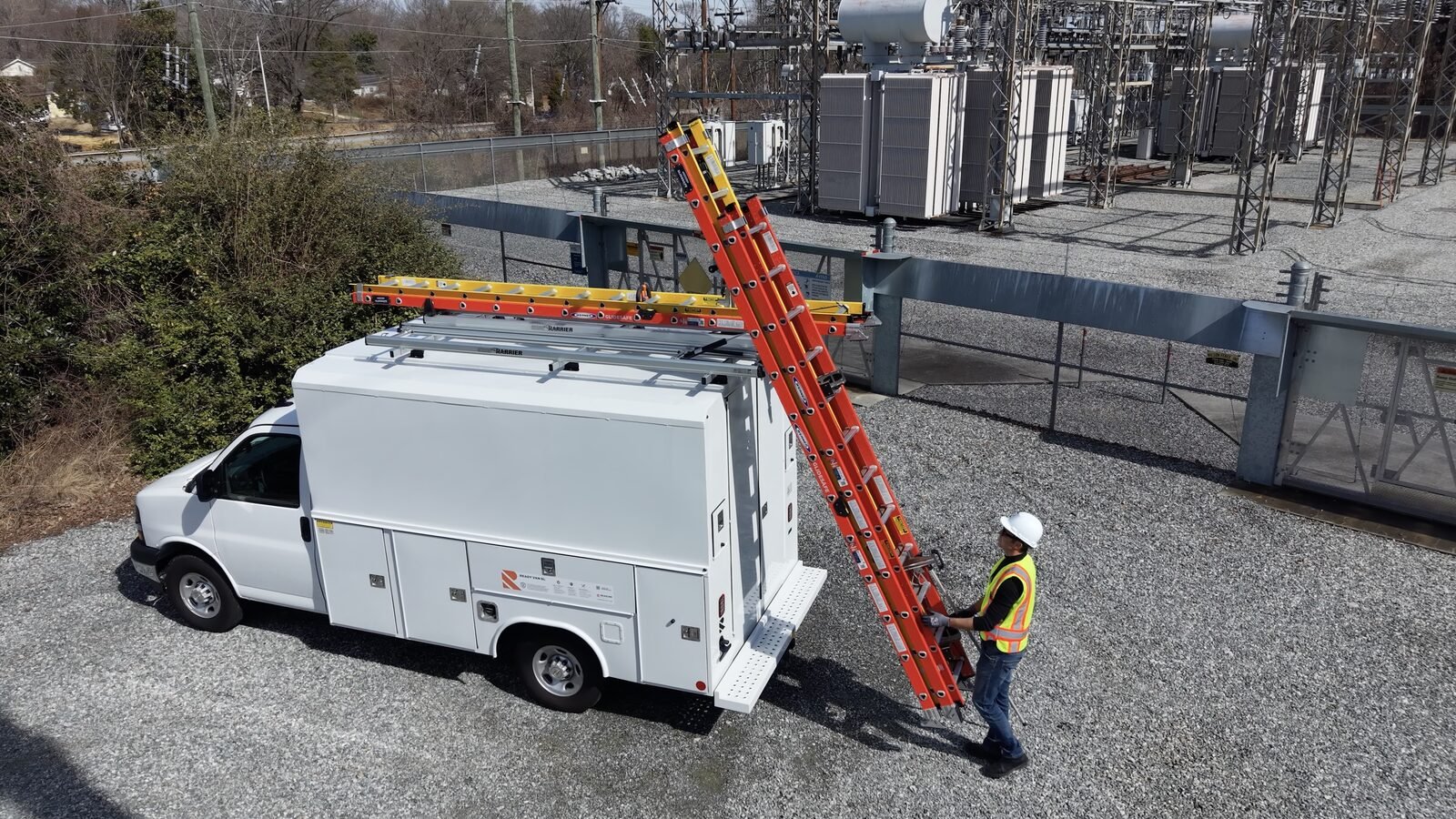 G2000 in action — worker unloading ladder from utility service body at electrical substation
